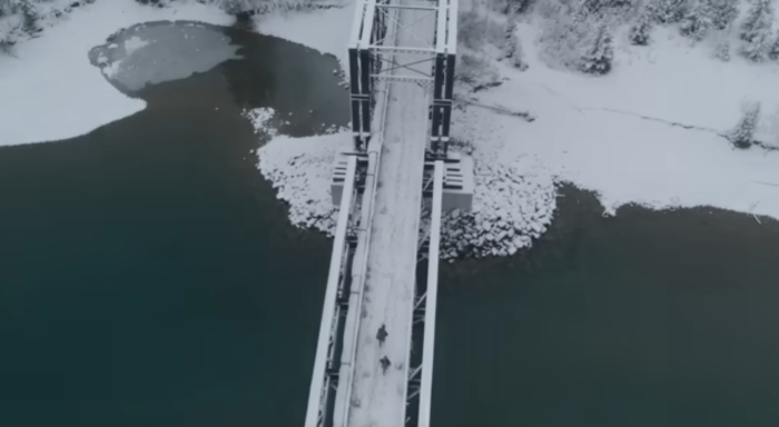 Two people are crossing a bridge
